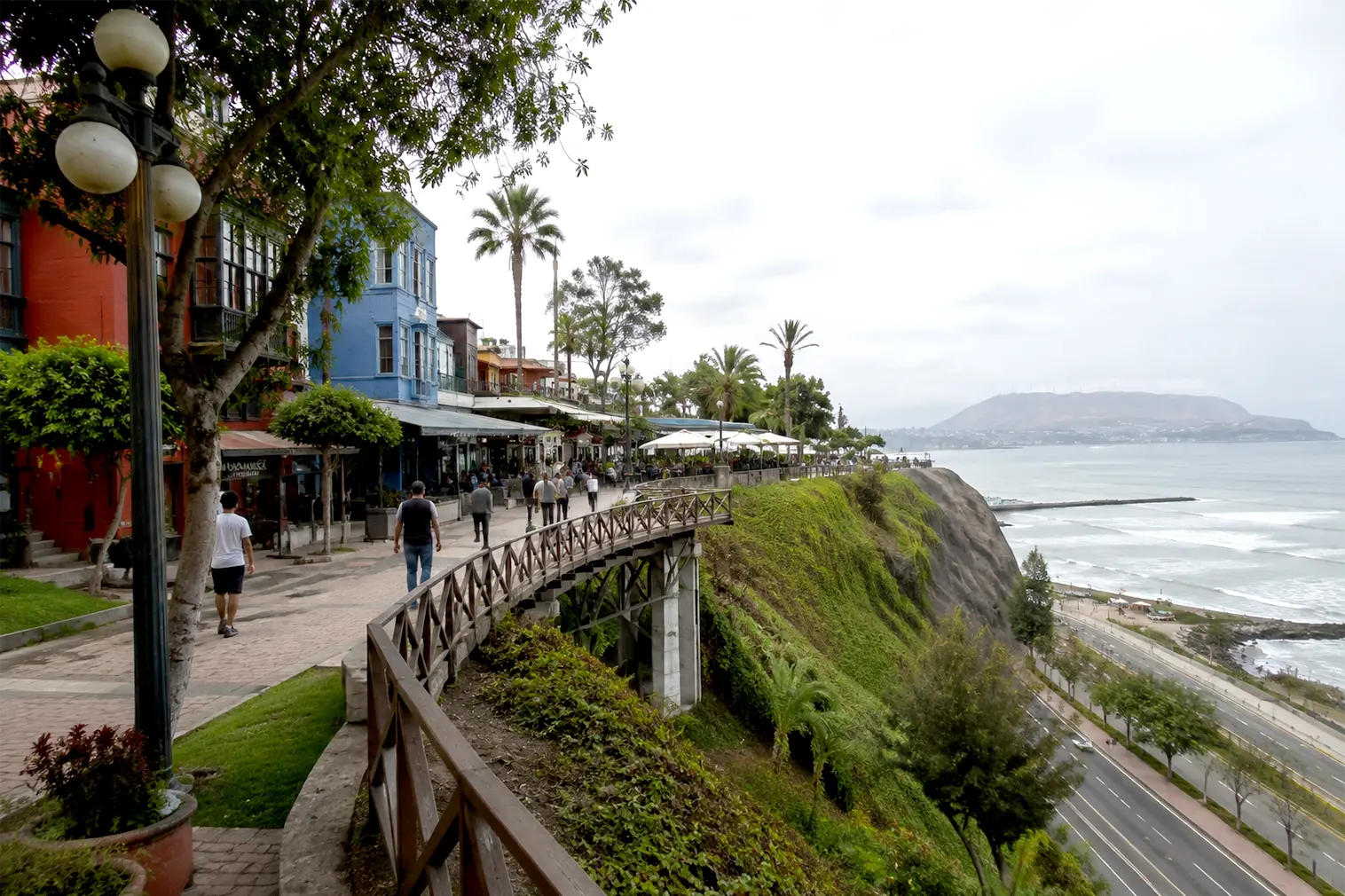 Pedestrians walking along the scenic cliffside Malecón boardwalk in Barranco, Lima, overlooking the Pacific ocean.